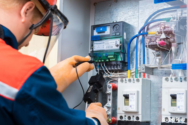 An electrician checks the functionality of the electric meter. 