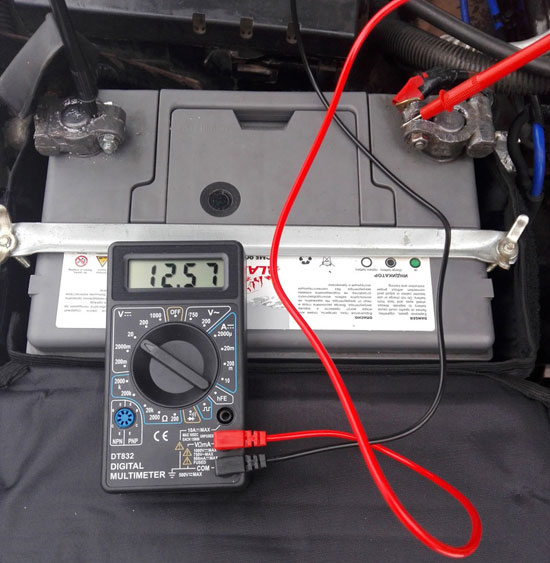 Measuring the voltage on the terminals of a car battery with a digital multimeter.